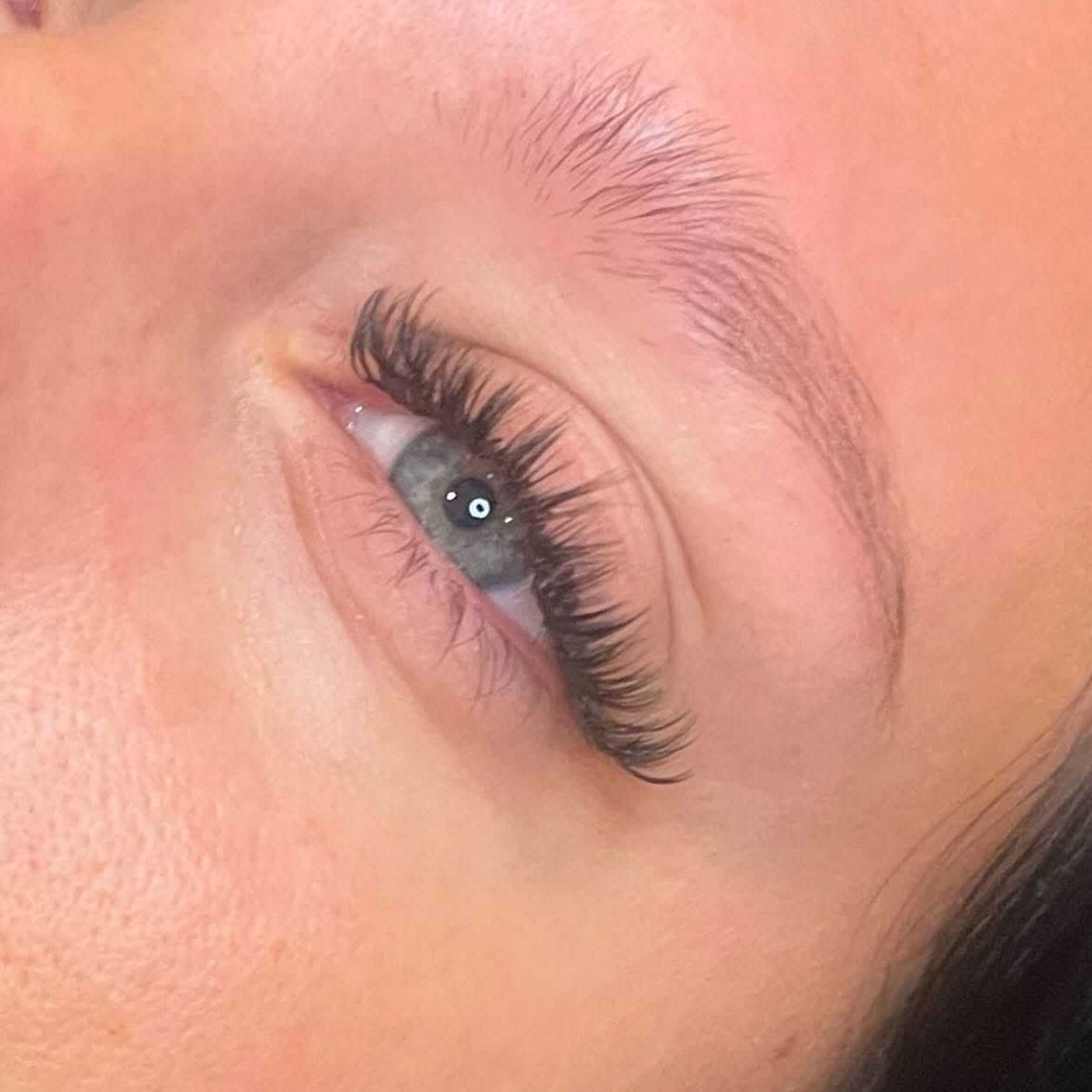 Close-up of a person's eye with long, curled eyelashes and well-groomed eyebrows.